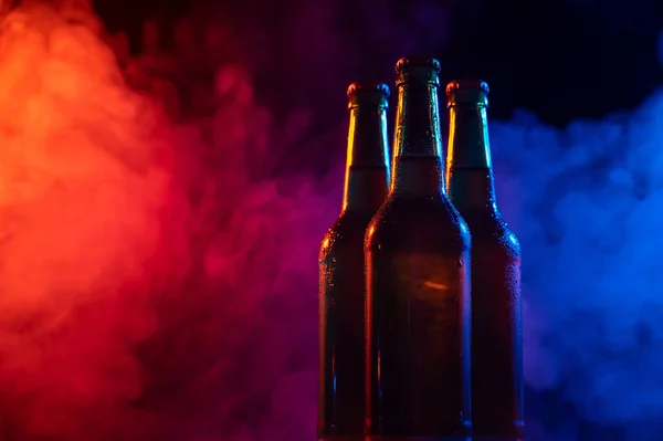 Tři láhve piva v modrorůžové mlze. — Stock fotografie