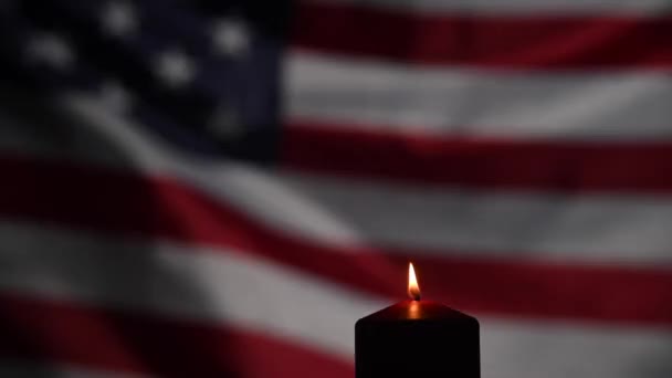 Burning candle against the background of the waving flag of the united states of america in the dark. — Stock Video