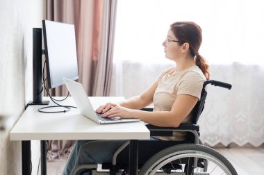 Tekerlekli sandalyedeki beyaz kadın laptopla çalışıyor.. 
