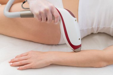 Lazer epilasyon prosedürü uygulayan bir kadın. İstenmeyen bitki örtüsünün donanımla kaldırılması
