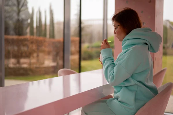Kafkasyalı kızıl saçlı kadın bir kafede tek başına otururken plastik kaşıkla dondurma yiyor.. — Stok fotoğraf