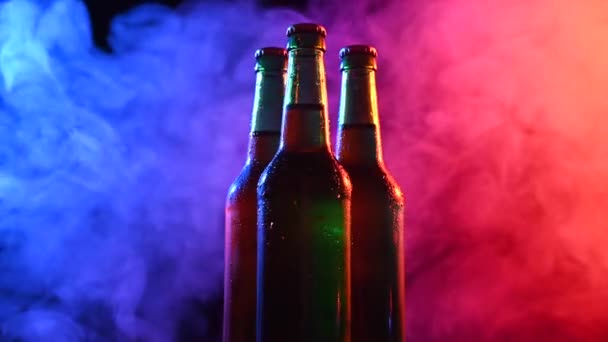 Three bottles of beer spinning in blue pink fog. — Stockvideo