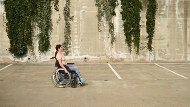 Vrouw in een rolstoel op een parkeerplaats. — Stockvideo
