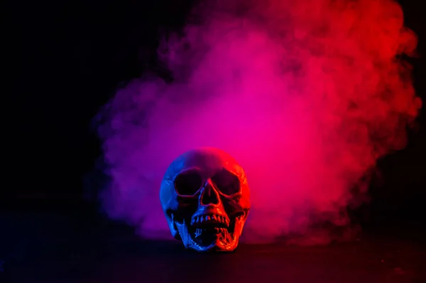 Crânio humano em rosa e azul fumaça em um fundo preto. Halloween.. — Fotografia de Stock