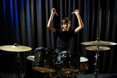 Bir çocuk kayıt stüdyosunda davul çalıyor.