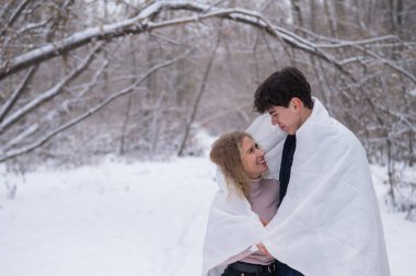 Genç bir çift kışın parkta yürür. Adam ve kız dışarıda beyaz bir battaniyeye sarılıp öpüşüyorlar..