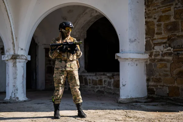 Blanke vrouw in een beschermend pak met machinegeweer. Vrouwelijke militaire man in camouflage uniform met wapens. — Stockfoto