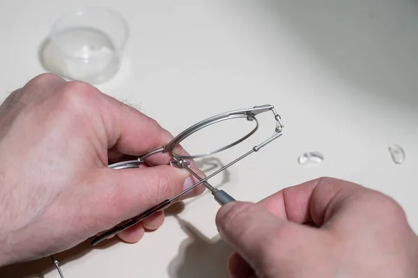 Montaż wkładek do nosa w okularach. Męski technik naprawia rozbite okulary. — Zdjęcie stockowe