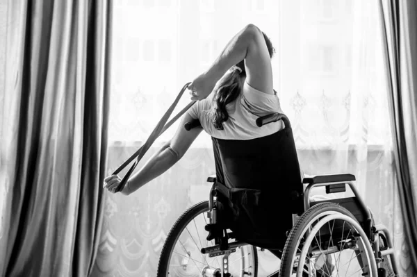 Běloška na invalidním vozíku cvičí s pomocí fitness gumiček. — Stock fotografie