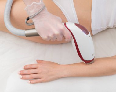 Lazer epilasyon prosedürü uygulayan bir kadın. İstenmeyen bitki örtüsünün donanımla kaldırılması