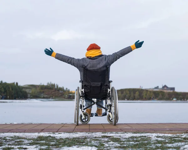 Blanke vrouw in een rolstoel wandelingen door het meer in de winter. — Stockfoto