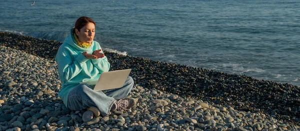 Mulher caucasiana falando por link de vídeo no laptop enquanto está sentado na praia. — Fotografia de Stock