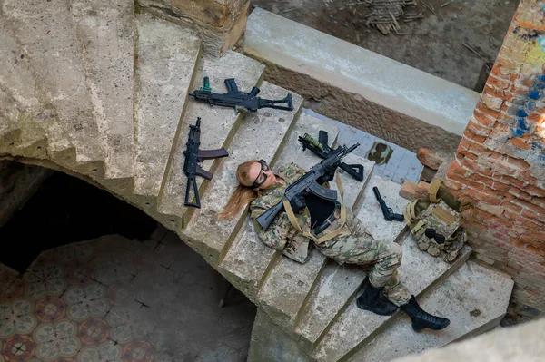 Mujer caucásica en uniforme militar yace en las escaleras de un edificio abandonado y sostiene una ametralladora. Vista desde arriba. —  Fotos de Stock
