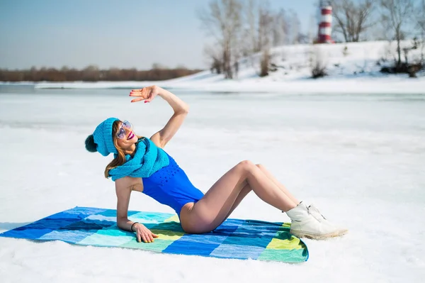 Beautiful caucasian woman in a swimsuit and a hat sunbathes on the snow. — Fotografia de Stock