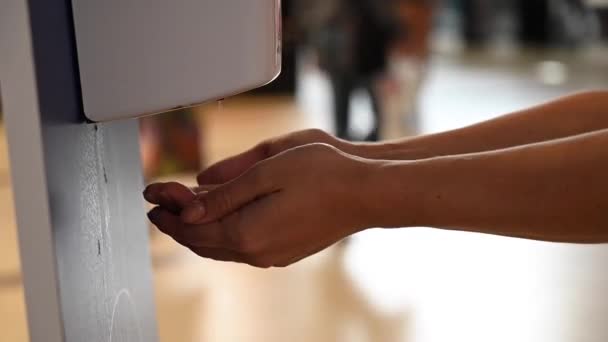 Uma mulher sem rosto limpa as mãos com um dispensador automático de desinfetantes no aeroporto. — Vídeo de Stock