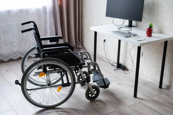 Miejsce pracy dla osoby niepełnosprawnej. Wózek inwalidzki przy stole z komputerem. — Zdjęcie stockowe