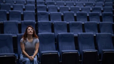 Kafkasyalı kızıl saçlı kadın boş bir salonda sinemada ön sırada oturuyor. Kız tek başına film izliyor.. 