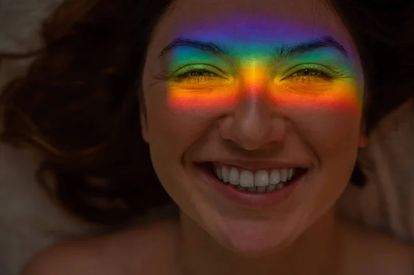 Close-up retrato de mulher sorridente com raio de luz do arco-íris em seu rosto. — Fotografia de Stock