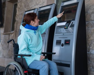 Tekerlekli sandalyedeki beyaz kadın self-servis kasasından tren bileti alıyor.. 