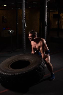 Beyaz bir adam spor salonunda araba lastiği itiyor.. 