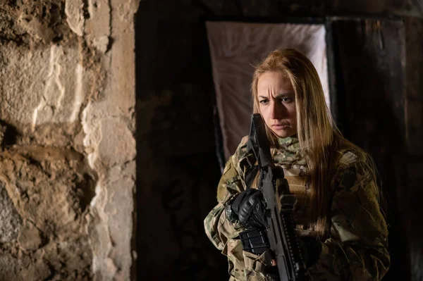 Mujer caucásica en uniforme del ejército sosteniendo una ametralladora y de pie cerca de un ataúd abierto. — Foto de Stock