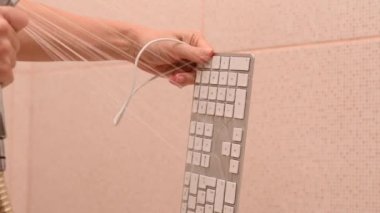 Yakın plan kadın akan suyun altında beyaz bilgisayar klavyesini yıkıyor..