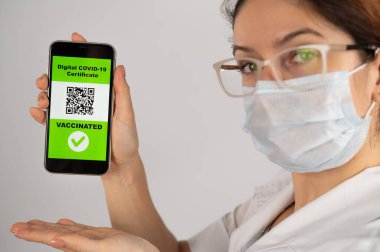 Doktor aşı öneriyor ve QR kodlu bir akıllı telefon tutuyor..