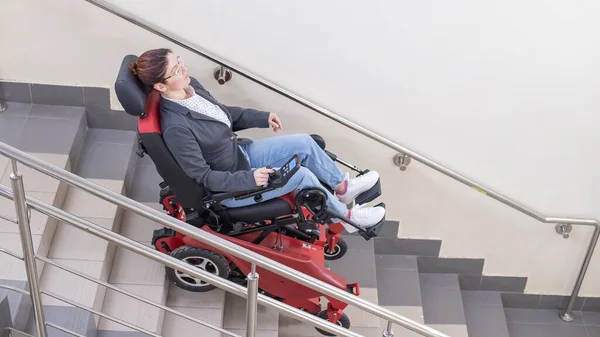 Caucasian woman in electric caterpillar wheelchair climbs up stairs. — Stock Photo, Image