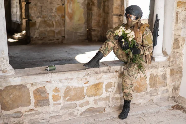 Mujer caucásica en uniforme militar con una ametralladora y un ramo de rosas blancas. —  Fotos de Stock