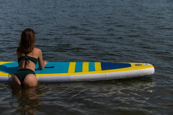 Vacker kaukasisk kvinna simmar på en SUP styrelse. — Stockfoto