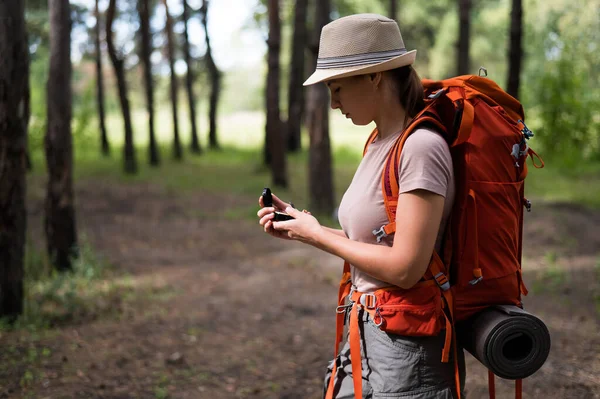 Jeune femme caucasienne fait de la randonnée et utilise une boussole dans la forêt. — Photo