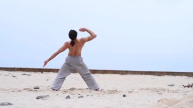 Kafkasyalı, uzun saçlı, dışarıda qigong antrenmanı yapan bir adam.. 