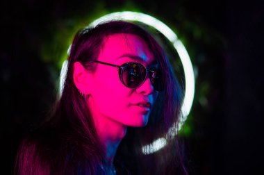 Neon ışıkta güneş gözlüğü takan Asyalı adamın portresi. 