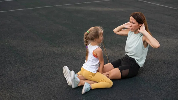 Matka a dcera chodí ven na sport. Běloška a holčička jsou zapojeny do fitness na stadionu. — Stock fotografie