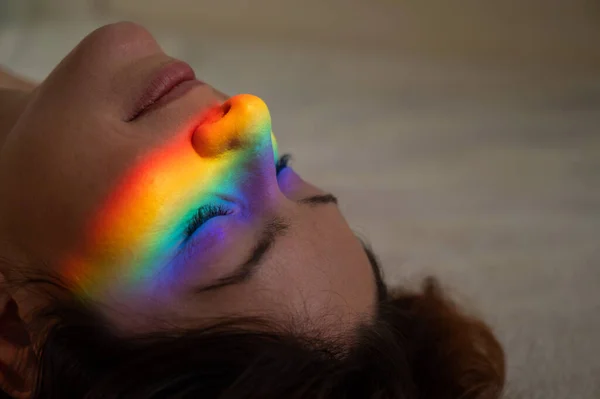 Close-up portrait of caucasian woman with ray of rainbow light on her face. — Fotografia de Stock