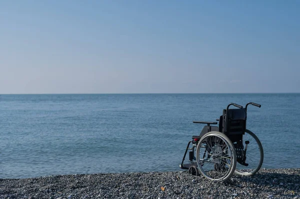 En tom rullstol på en stenig strand. — Stockfoto