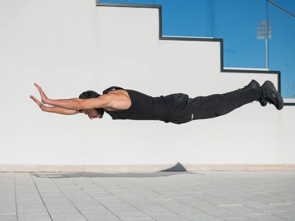 Siyah spor kıyafetli bir adam dışarıda şınav çekerken zıplıyor.. — Stok fotoğraf