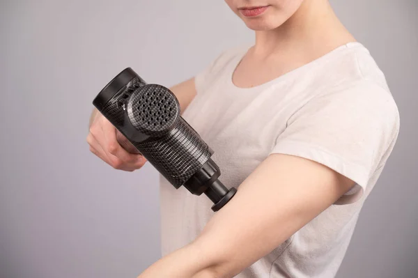 白人女性は腕の筋肉の痛みのためにマッサージ銃を使用しています. — ストック写真