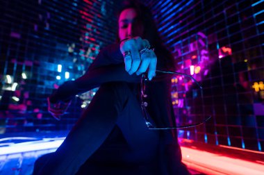 Asyalı adam güneş gözlüğü tutuyor. Neon fotoğraf stüdyosu. 