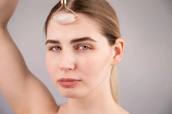 Detailní záběr portrét ženy používá křemenný masážní válec k vyhlazení vrásek na čele. — Stock fotografie