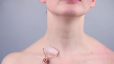 Boynundaki kırışıklıklara karşı alternatif bir dövüş için kuvars silindirli masaj aleti kullanan bir kadının yakın plan portresi. Venüs 'ün halkalarının yumuşaklığı. 