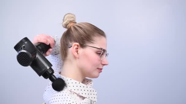Glimlachende vrouw met beugel maakt gebruik van een massager pistool voor haar rug. — Stockvideo
