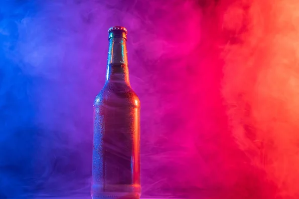 Стеклянная бутылка пива в голубом розовом тумане — стоковое фото