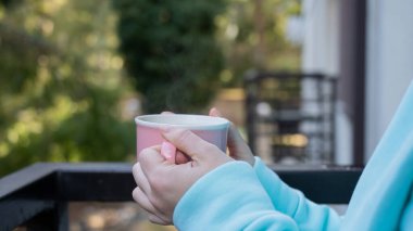 Balkonda sıcak bir şeyler içen bir kadın.. 