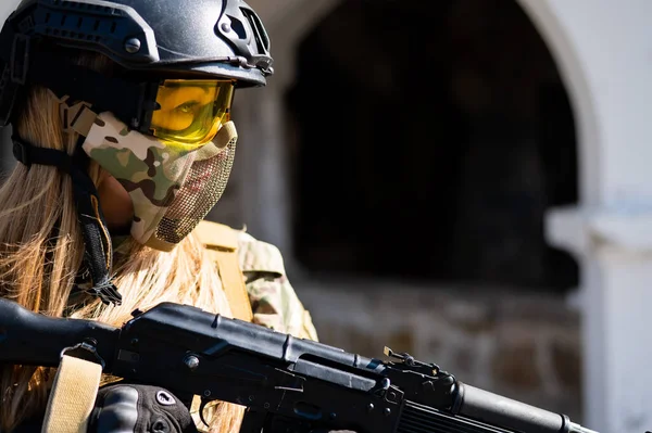 Mujer caucásica en traje protector con ametralladora. Una soldado con uniforme de camuflaje sostiene un arma. —  Fotos de Stock