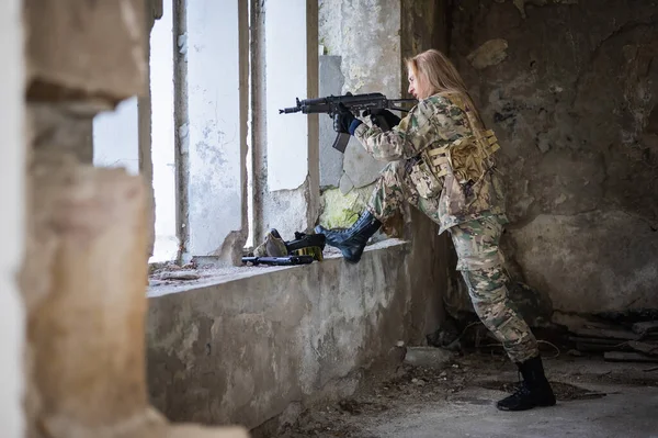 Žena v armádní uniformě si chce vystřelit ze zbraně v opuštěné budově.. — Stock fotografie