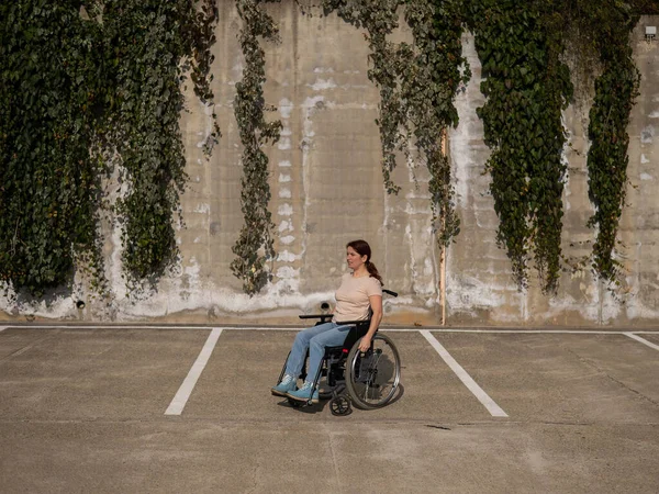 Femme en fauteuil roulant dans un parking. — Photo