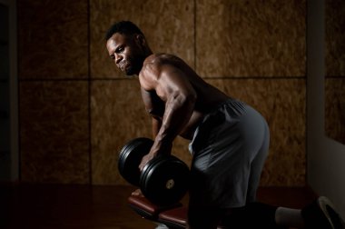 Çıplak gövdeli Afro-Amerikan bir adam trisepsli sıra yapıyor, halterli.. 