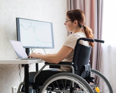 Tekerlekli sandalyedeki beyaz kadın laptopla çalışıyor.. 