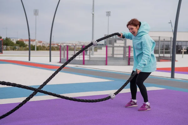 Vit kvinna i minttröja tränar med rep vid idrottsplatsen.. — Stockfoto